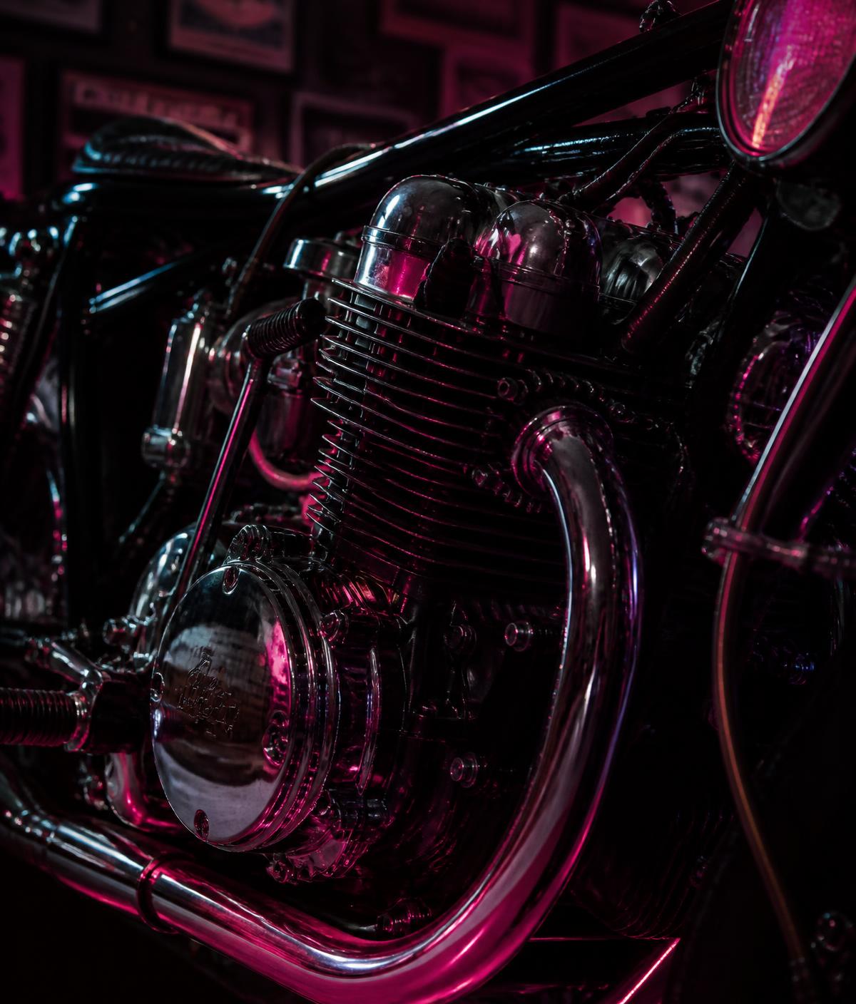 Chrome engine detail of a custom motorcycle under pink light
